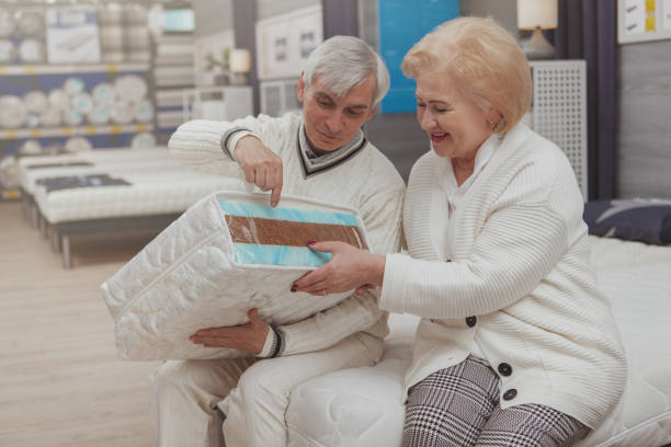 pareja de ancianos comprando en la tienda de muebles - colchón para personas mayores fotografías e imágenes de stock