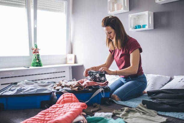 istock Woman sitting on bed and packing suitcase 1153039561
