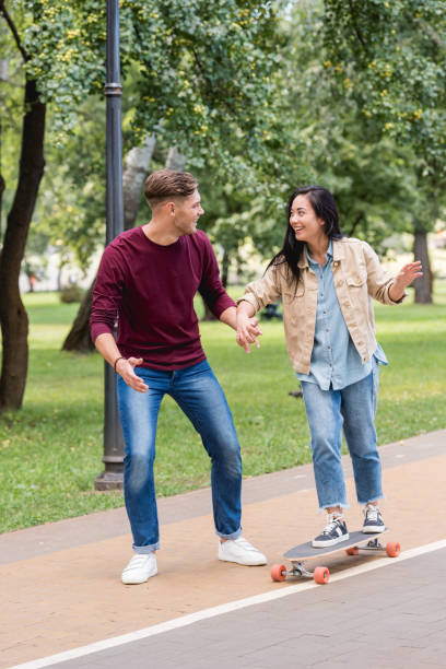istock handsome man looking at attractive girlfriend riding longboard 1153040953