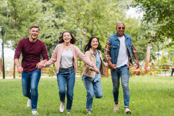 istock cheerful multicultural friends holding hands and running in park 1153041300