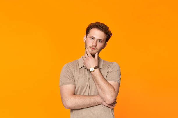 istock Young bearded confident man with hand raised on chin and looking at the camera. 1153042863