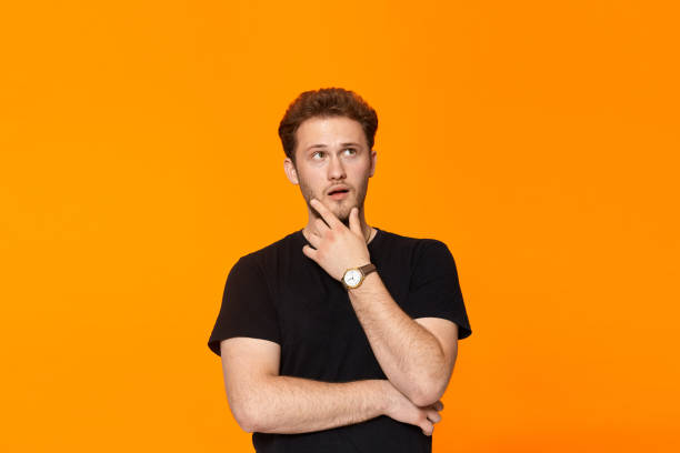 istock Young bearded confident man with hand raised on chin and looking at the camera. 1153042920