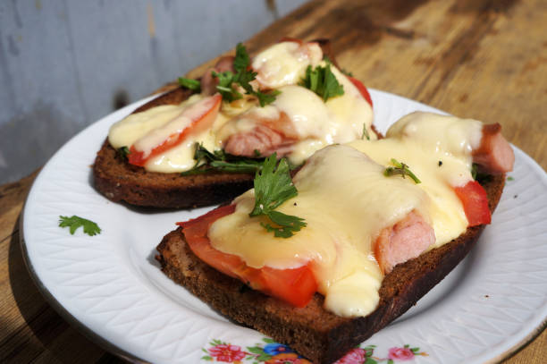 Hot sandwiches. Cheese, tomatoes and sausages on rye bread.