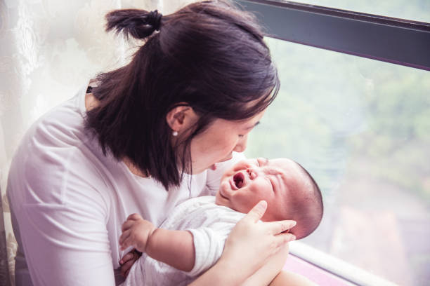 Mom holding asian baby sick and crying on stock photo