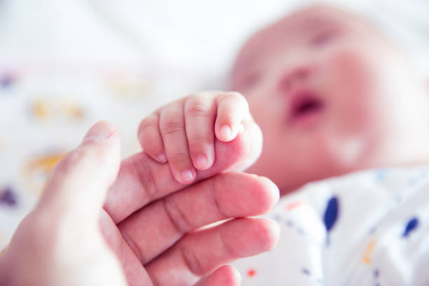 istock Newborn baby holding father's hand 1153045326