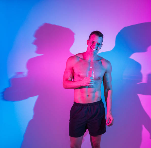 istock Shirtless young man holding a water bottle 1153046311