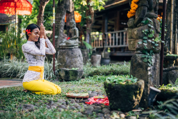 Woman practicing yoga with with canang sari - offering for Gods. Balinese tradition.
