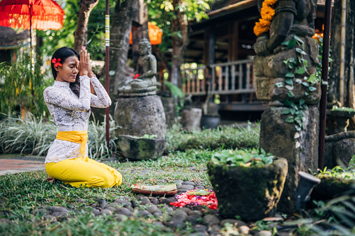 Woman practicing yoga with with canang sari - offering for Gods. Balinese tradition.