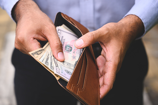 Close up hombre de negocios contando la propagación de dinero en efectivo en la billetera. photo