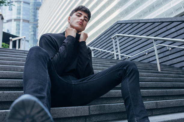 istock Handsome man in black clothing sitting on stairs 1153048251