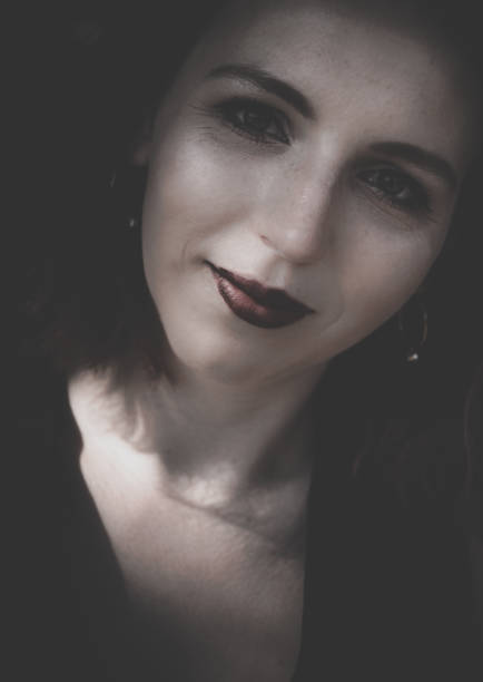 Attractive sincere brunette woman wearing makeup with a quiet smile in a close up cropped portrait of her face in shadows