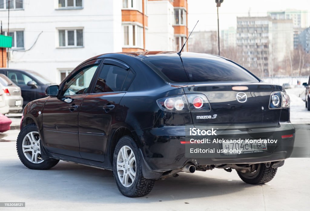  2008 Mazda 3 Vista trasera negra con interior gris oscuro en excelentes condiciones en un espacio de estacionamiento entre otras fotos de autos