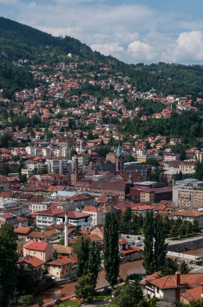 Sarajevo, Bosnia and Herzegovina, Western Balkans - July 8, 2018: aerial view of the skyline of the capital Sarajevo, surrounded by the Dinaric Alps and situated along the Miljacka River, seen from the top of Zuta Tabija (Yellow Fortress) sarajevo, bosnia y herzegovina, balcanes occidentales: vista aérea del horizonte de la capital sarajevo, rodeado por los alpes dináricos y situado a lo largo del río miljacka, visto desde la parte superior de zuta tabija (fortaleza amarilla)
