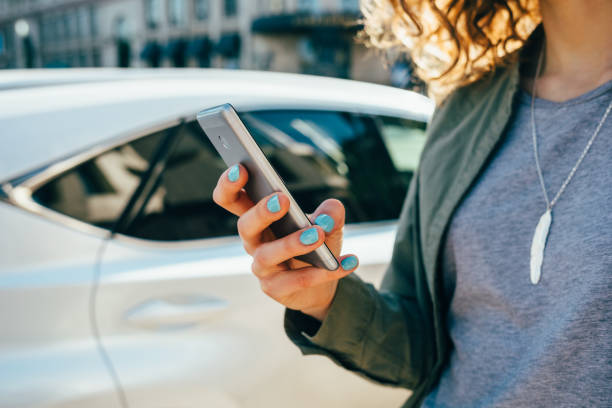 通りに立ってスマートフォンを使用して若い女性 - タクシー 写真 ストックフォトと画像