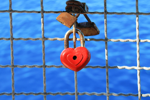 Red heart shape padlock on white fence