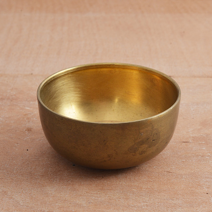 Ancient brass bowl for special ceremony on wooden table.