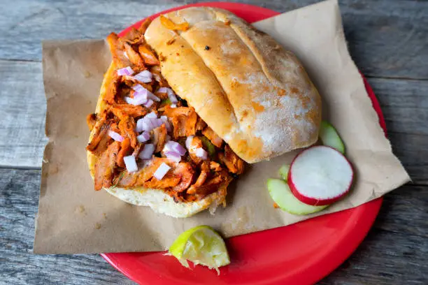 Mexican food: pork sandwich also known as "torta al pastor" on wooden background