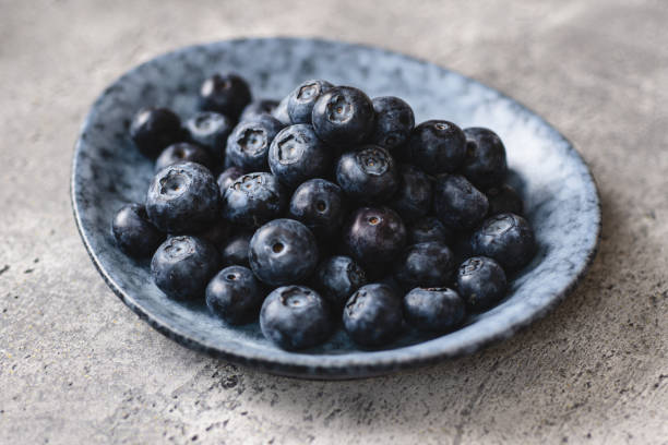 istock Fresh Organic Blueberries in Gray Plate on Dark Stone Background 1153076396