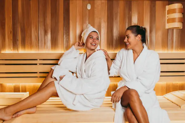Two beautiful young women relaxing in SPA sauna room.