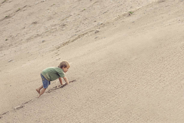 istock Boy Climbing On The Sand dune. Summer day 1153081527