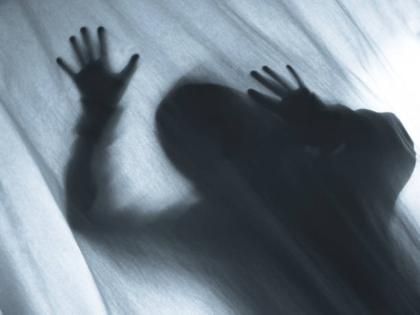 istock Screaming human pressing through fabric curtain as horror background . Trapped in shadows 1153088028