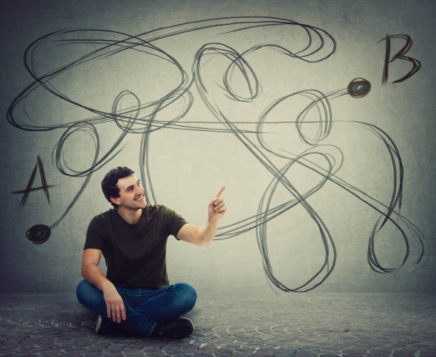 istock Young man sitting on the floor pointing forefinger finding the correct way from point A to point B. Solving problem, find solution, business idea and creativity 1153091069