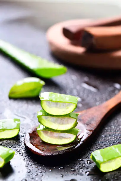 aloe vera slices with wooden spoon and sandal wood in background, water drops, beautiful images, fresh concept, wallpaper