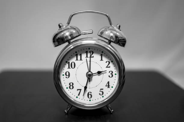 istock Silver alarm clock on the table with white behind 1153096662