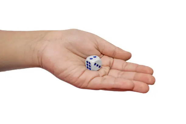 Dice in the palm of hand on white surface and fingers.