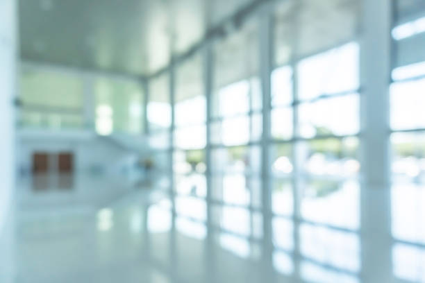 istock Office building lobby hall blur background or blurry school hallway corridor interior view looking toward empty entrance, glass curtain wall and floor with exterior light illumination 1153114934