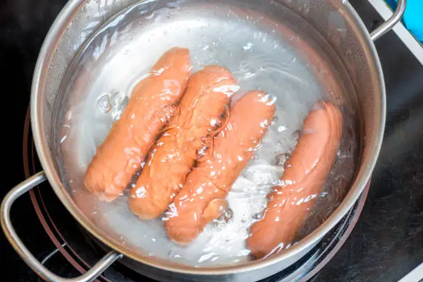 Photo of sausages are boiled in a pan in boiling water, close-up shot