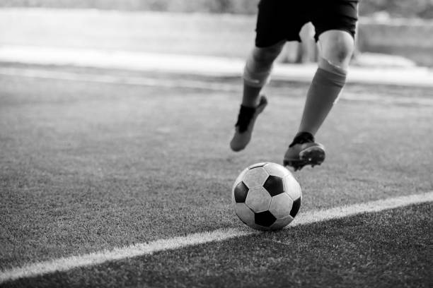 black and white image of the soccer player shoot ball on artificial turf. black and white image of the soccer player shoot ball on artificial turf. football academy. the black ball stock pictures, royalty-free photos & images