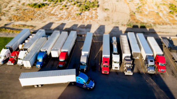 Drone View Using Tilt-Shift With Blurred Motion Of Semis Parked Side By Side In A Parking Lot Aerial drone view of semis lined up in a row using tilt-shift making them look like toys tilt shift stock pictures, royalty-free photos & images