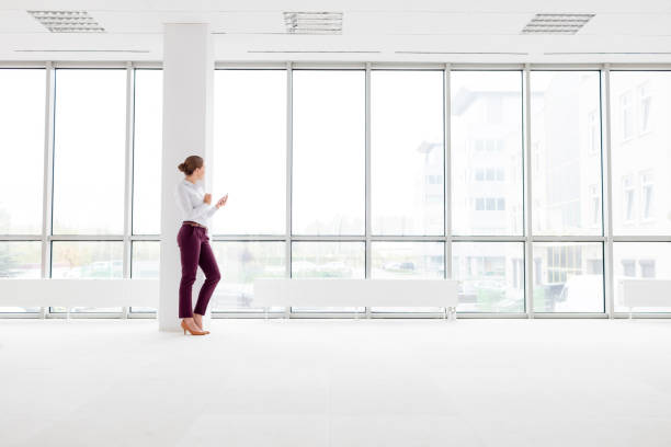 istock Young businesswoman leaning on column at new empty office 1153146840