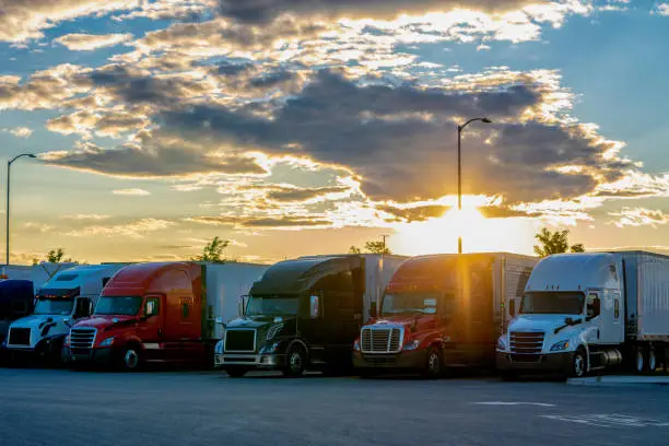 A beautiful sunset behind neatly parked semis in a parking lot