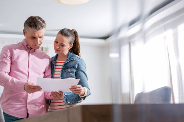 istock Couple reading agreement paper while standing in apartment 1153150451