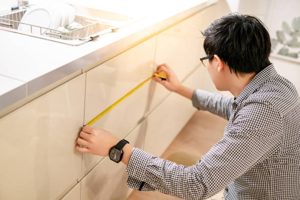 istock Asian man using tape measure on kitchen counter 1153156586