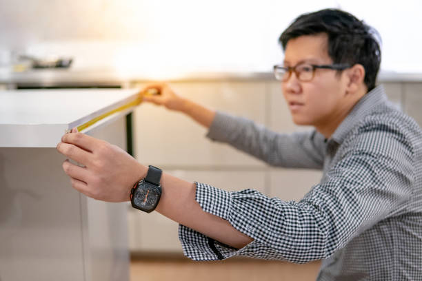 istock Asian man using tape measure on kitchen counter 1153156694