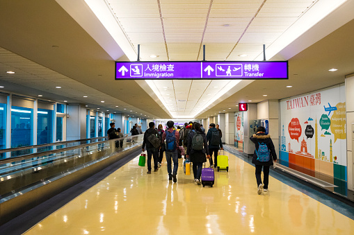 Taipei, Taiwan- May 2019: Immigration and Transfer signs with travelers at Taiwan Taoyuan International Airport.