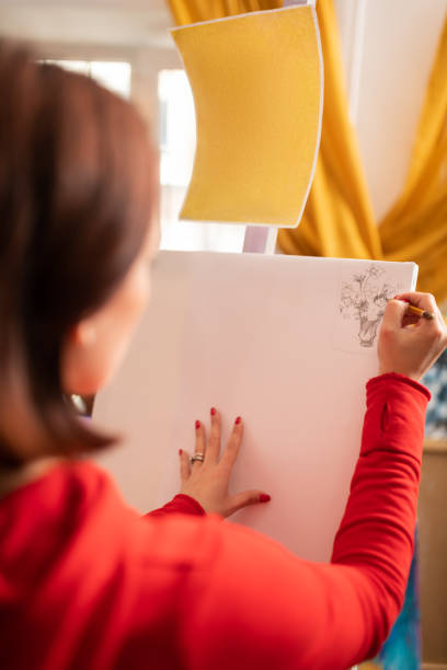 istock Young artist with red nails drawing on white canvas 1153161191