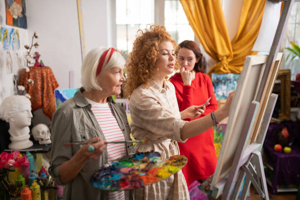 istock Aged teacher looking at her student drawing on canvas 1153161219