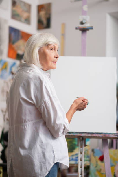 istock Woman wearing white blouse standing near canvas in workshop 1153161246