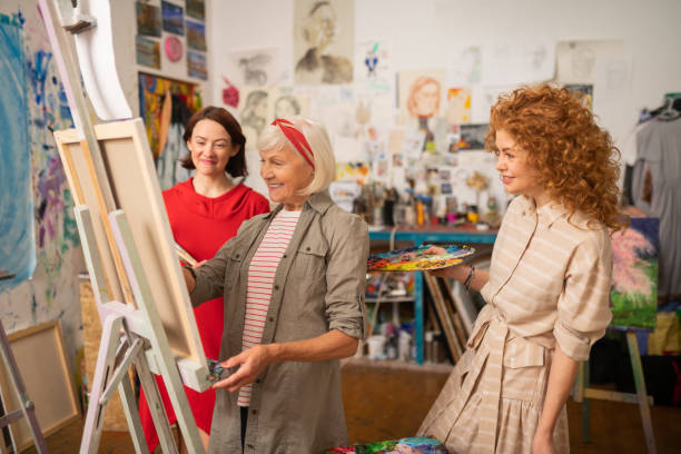 istock Students and art teacher smiling while painting and talking 1153161259