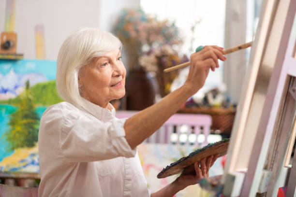 istock Cheerful blonde-haired woman feeling relieved while painting 1153161269