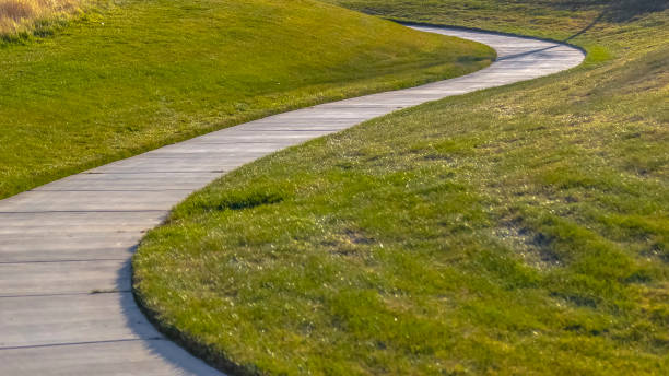 istock Panorama frame Walkway that winds through a rich grassy field at a park with playground 1153164816