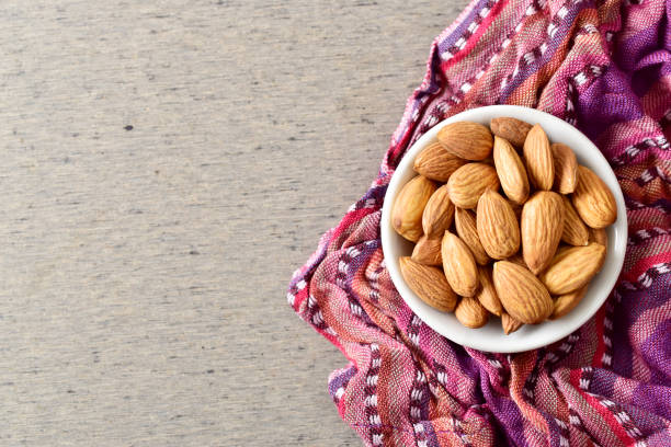 istock almonds in white bowl on purple cloth with grey background 1153165678