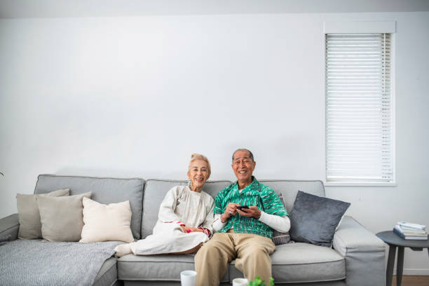 istock Lighthearted Senior Japanese Couple Relaxing on the Sofa 1153165859