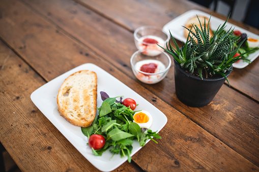 The day begins with a delicious breakfast of toasted bread, salad, and yogurt on a wooden dining table.