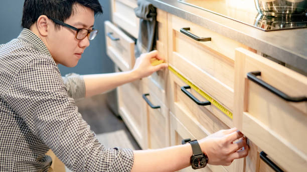 istock Asian man using tape measure on kitchen counter 1153169315