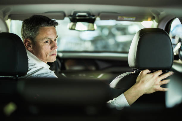 homme d’affaires mi-adulte s’inversant en allant sur un voyage en voiture. - car driving men reversing photos et images de collection